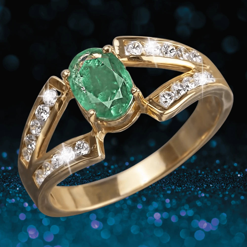 Emerald Orchard Ring featuring a sterling silver band plated in gold, with a central green emerald stone and sparkling clear gemstones accented along the split shank design.