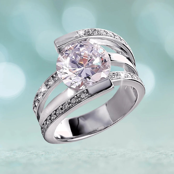 Rodela Rhodium Ring designed for women, featuring sterling silver with rhodium plating and a large clear stone centerpiece accented by smaller sparkling stones along the band.