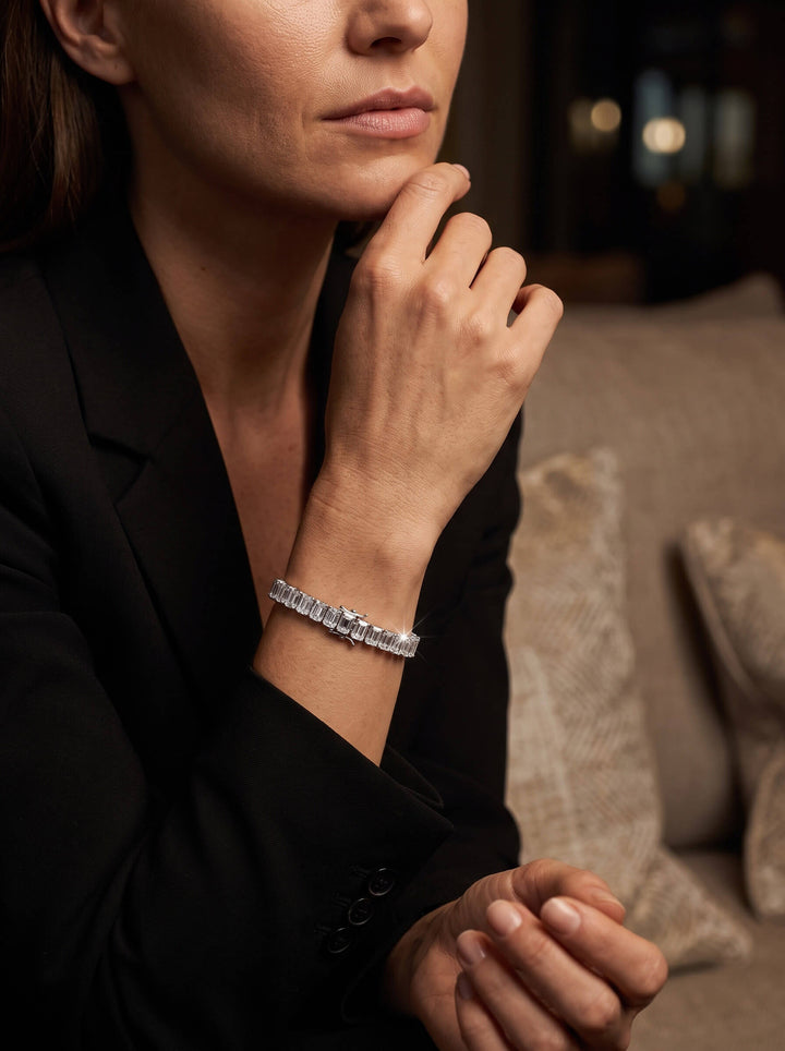 Fifth Avenue Emerald-Cut Bracelet worn on a woman's wrist featuring a refined row of sparkling rectangular stones against a black blazer