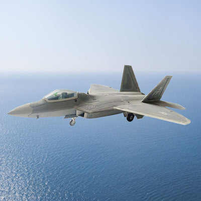 F-22A Raptor fighter jet flying over the ocean with landing gear lowered and twin tail fins visible