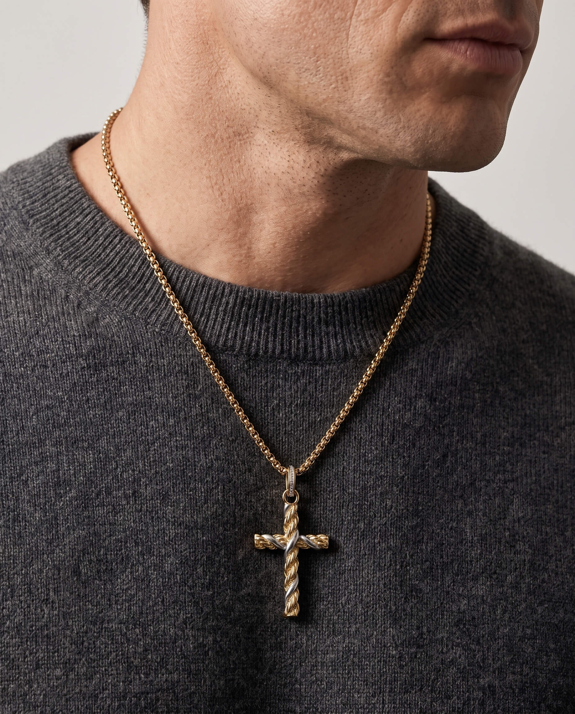 Man wearing a gold Entwinned Cross Pendant necklace with a textured twisted design on a gold chain over a dark gray sweater, up to 75% off retail.