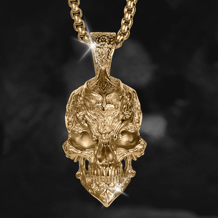 Ornate gold skull pendant necklace with detailed sculpted features and a chunky chain against a dark black background