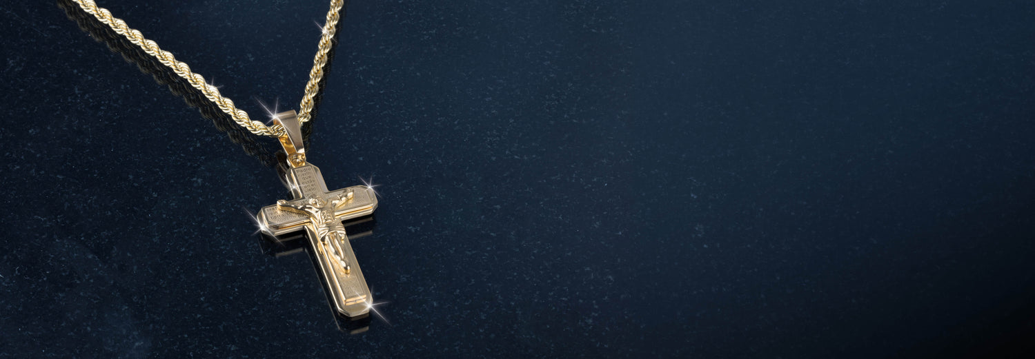 Gold cross pendant necklace resting against a dark textured background with polished surfaces catching the light