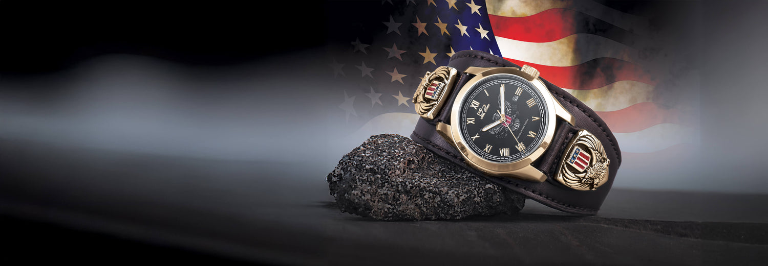 Watch with a black strap on a dark surface, American flag in the background