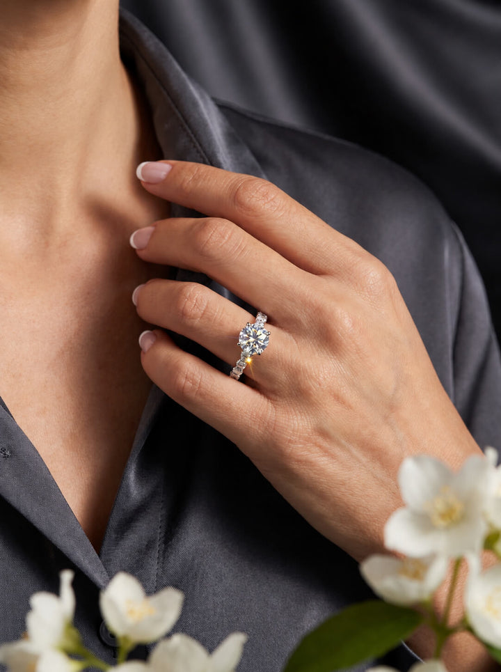 Grandeur Radiance Ring featuring a sparkling cluster gemstone design worn on a woman's hand against elegant black fabric jewelry styling
