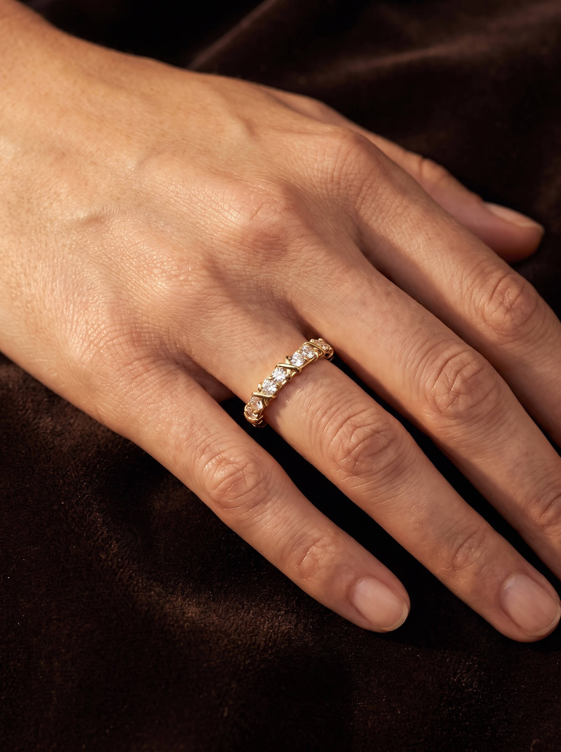 Golden Kiss Ladies Ring with a sparkling gold band and clear stones worn on a hand against dark satin Up To 75% Off Retail