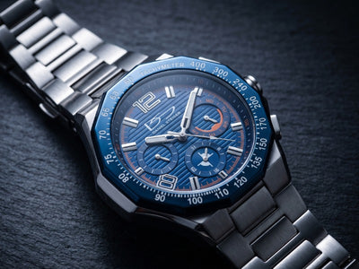 Ultima Men's Watch with a blue chronograph dial silver metal bracelet and tachymeter bezel on a dark textured surface Up To 75% Off Retail