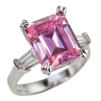Pink Billionaire Ladies Ring featuring a large emerald-cut pink gemstone set in rhodium-plated sterling silver with tapered baguette side stones, elegant jewelry for women.